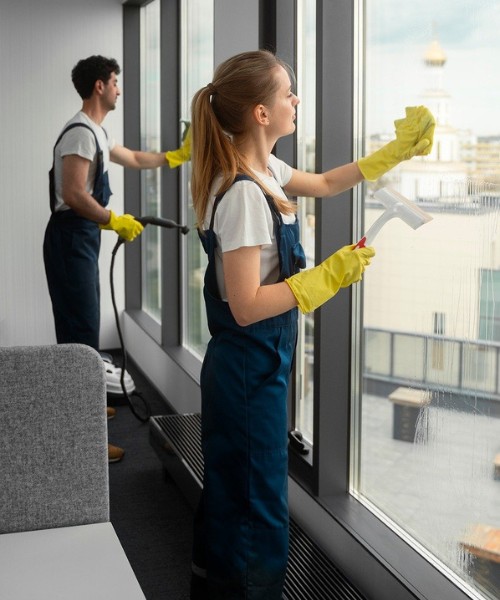 commercial cleaning services team cleaning interior office windows with squeegee and spray