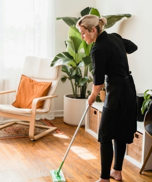 Commercial cleaning services professional mopping a hardwood floor in a modern lounge